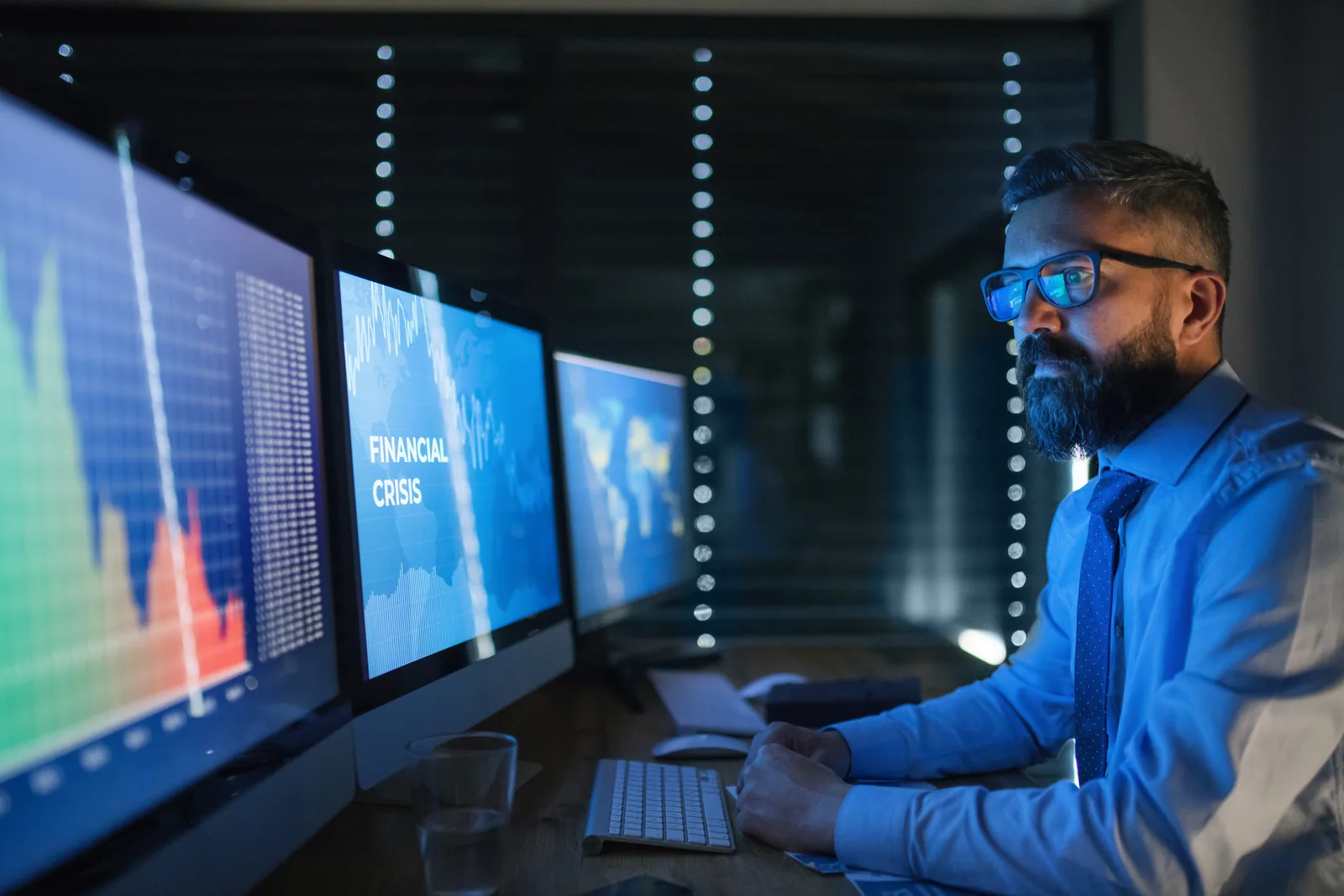 Analyst reviewing business data across multiple monitors
